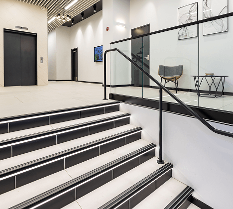 Perimeter strip lighting along a lobby staircase aids wayfinding while brightening an area with minimal natural light without creating glare.