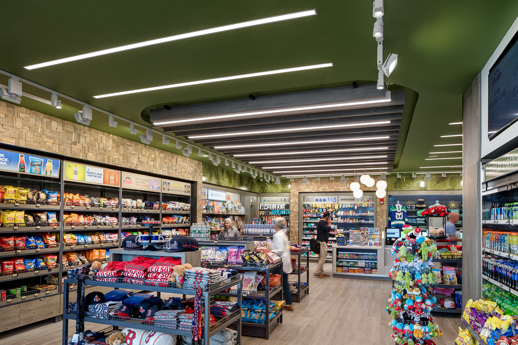 Linear LED pendants provide general lighting over retail aisles, while track lights highlight products on a display wall.